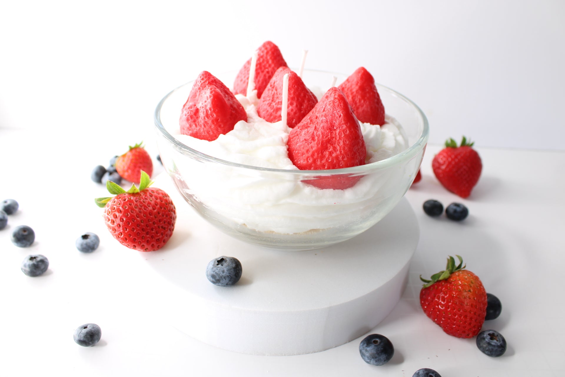Bowl of whipped cream  with strawberries and blueberries on a white background