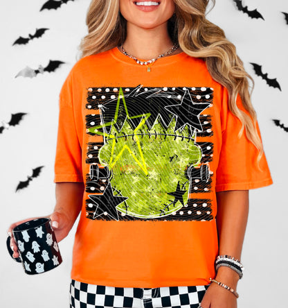 A woman wearing a bright orange graphic t-shirt with a stitched pumpkin and black star design, holding a black mug with white ghosts, set against a white wall with black bat silhouettes.